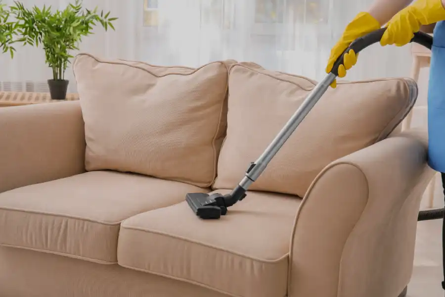 Fabric couch being vacuumed with an upholstery attachment